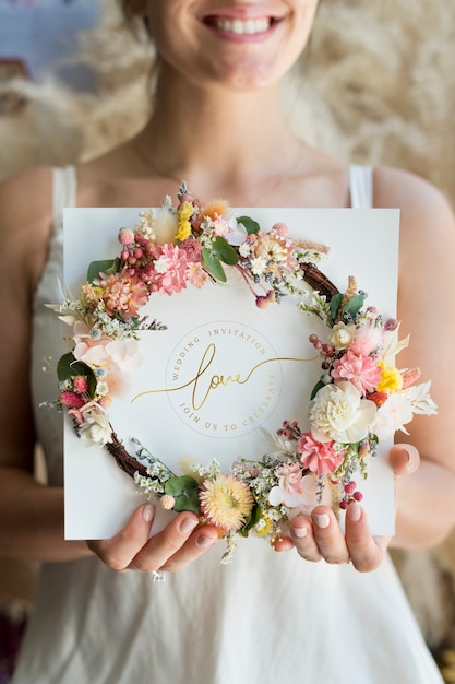 Noiva segurando uma coroa de flores com um convite de casamento