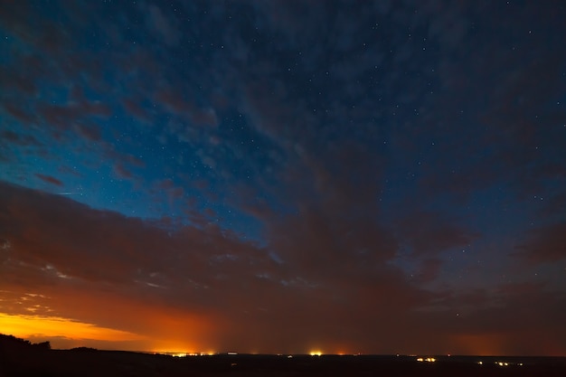 Foto nuvens à noite contra o fundo de estrelas brilhantes no céu após o pôr do sol