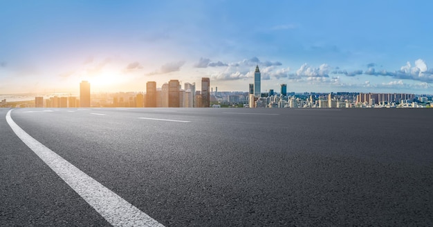 Offene Straße zur städtischen Skyline bei Sonnenuntergang