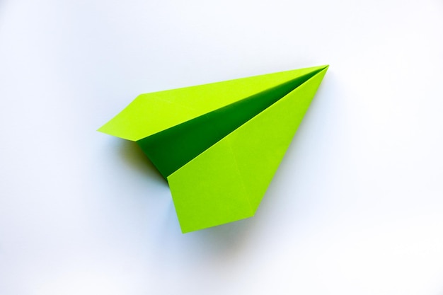 Origami de avião de papel verde isolado em um fundo branco