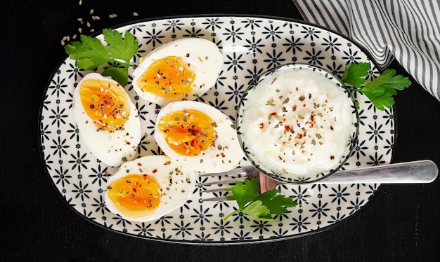 Ovos cozidos com iogurte, pimentão, salsa e xícara de chá Comida de dieta saudável para o café da manhã Vista superior plana