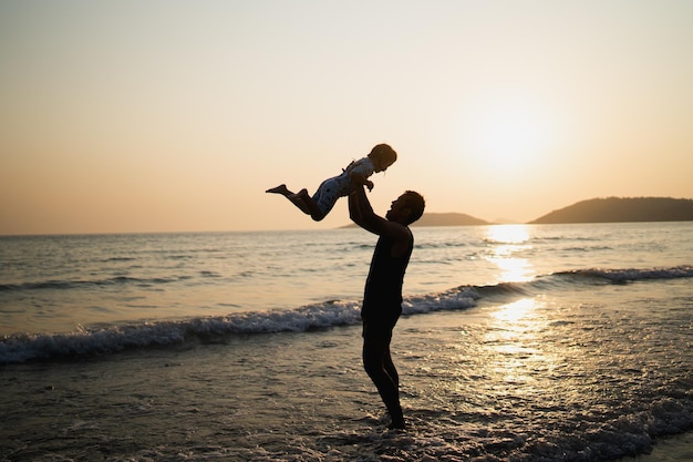 Pai segurando filha jogada no céu na praia o mar ao pôr do sol atividades familiares viagens marítimas praias arenosas e pôr do sol