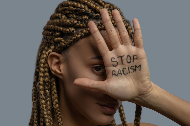 Foto pare o racismo. jovem afro-americana cobrindo um olho com a palma da mão com as letras de stop racism