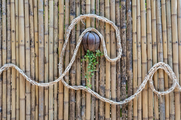 Parede de bambu decorada com uma corda e um vaso de flores de coco em uma praia tropical na Tailândia