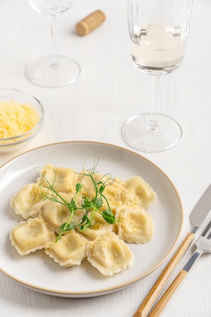 Foto pasta de ravioli italiano caseiro recheada com queijo com microgreens servida com vinho branco