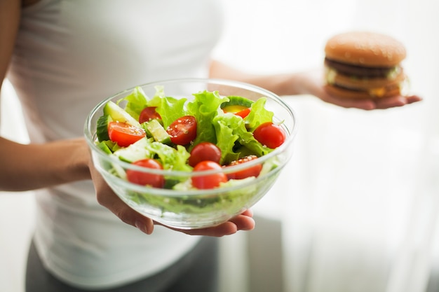 Peso de medição de medição da mulher na escala de peso que guarda o hamburguer e o Salat.