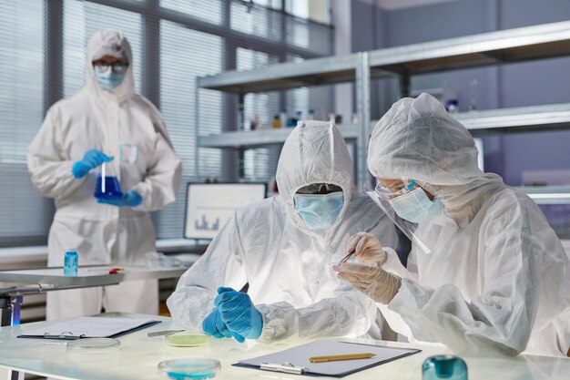 Foto pessoas com roupas de proteção trabalhando no laboratório