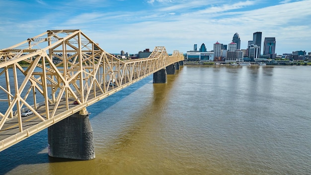 Ponte de ouro branco sobre a água do rio marrom escuro, arranha-céus aéreos do Rio Ohio, Louisville, no centro da cidade