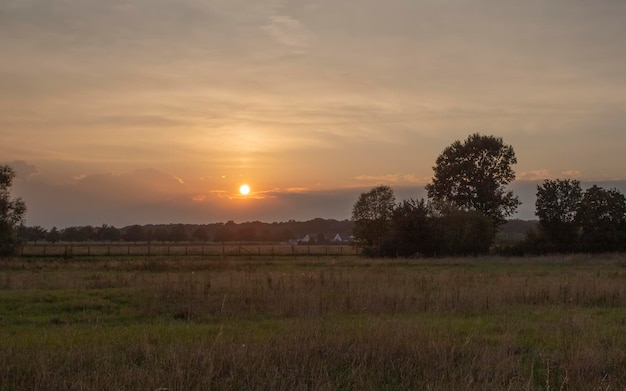 pôr do sol brilhante no campo de verão com feno e nuvens