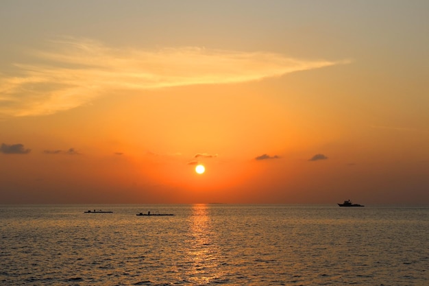 Pôr do sol na ilha das Maldivas com barco e reflexo da luz do sol na vista do mar do barco de viagem