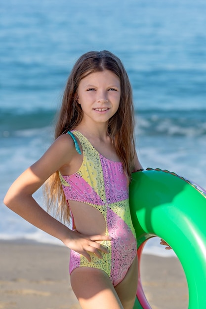 Porträt eines glücklichen Teenagermädchens mit einem aufblasbaren Gummiring, das am Strand Spaß hat