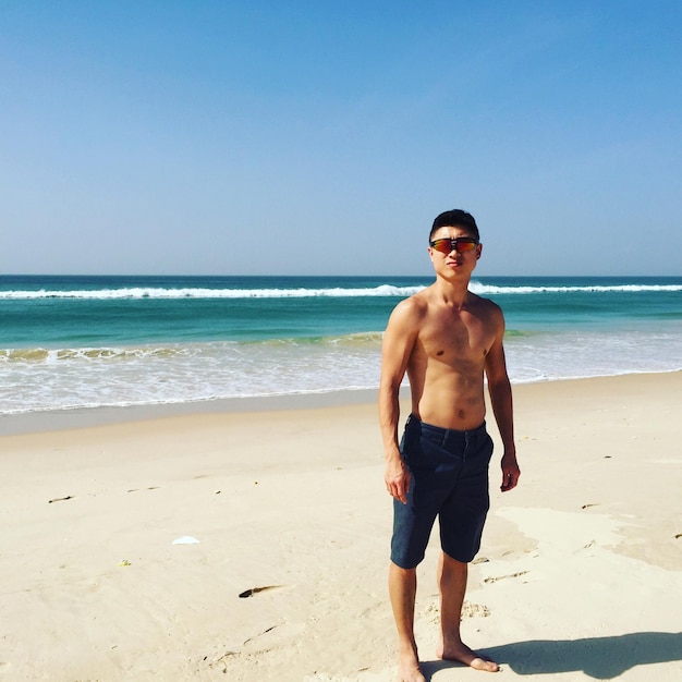 Foto porträt eines hemdlosen mannes, der am strand gegen den himmel steht