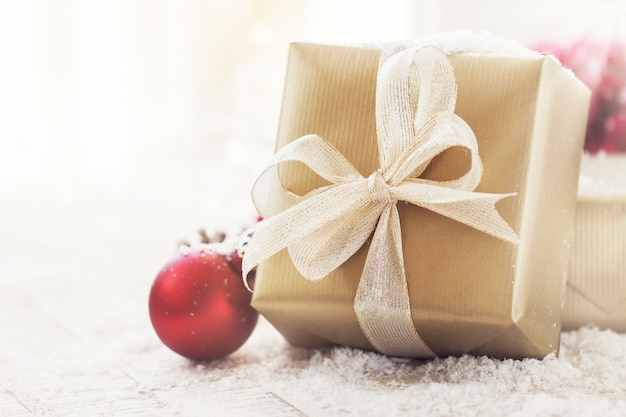 Presentes de Natal ou presentes com elegantes decorações de arco e natal no fundo nevado brilhante, conceito de Natal, horizontal