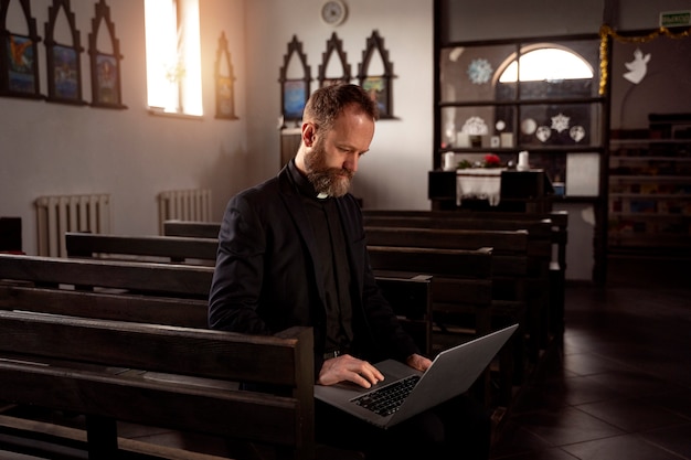 Priester mit Laptop hautnah