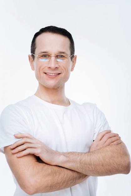 Foto pronto para trabalhar. homem inteligente positivo e confiante em pé contra um fundo branco e sorrindo enquanto está pronto para trabalhar