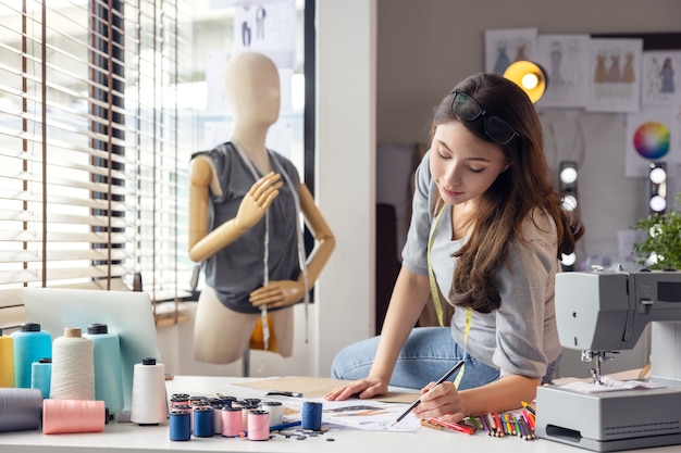 Proprietário de empresa com fita métrica trabalhando na moda, sentado na mesa