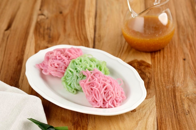 Foto putu mayang oder petulo ist ein traditioneller indonesischer snack, der aus reismehlsträngen hergestellt wird, die in einer kugel zusammengerollt werden und mit kokosmilch und palmzuckersirup serviert werden.