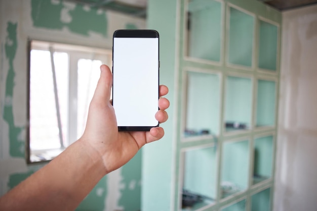 Reparação do quarto. Telefone móvel à disposição na perspectiva da construção