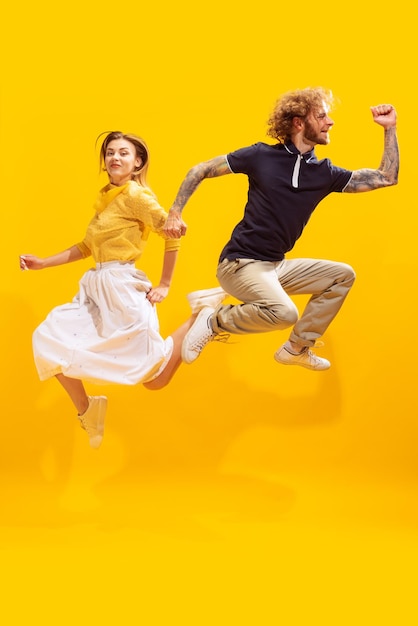 Retrato de jovem alegre e mulher posando em um salto isolado sobre o fundo amarelo do estúdio