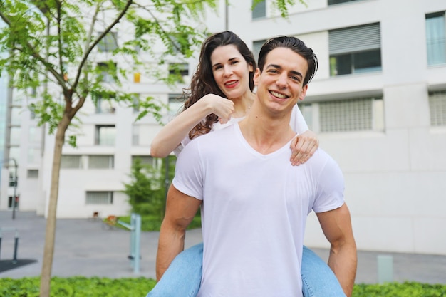 Foto retrato de um jovem casal sorridente contra o edifício