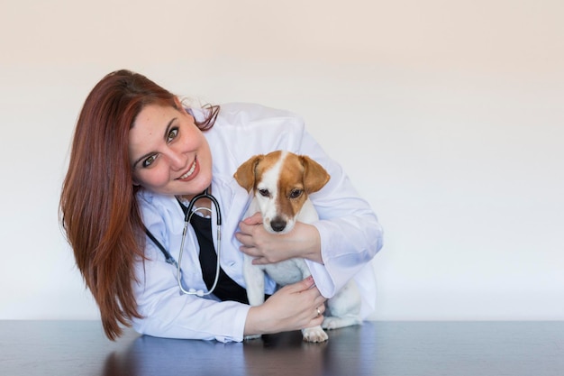 Foto retrato de um veterinário sorridente segurando um cão em uma mesa no hospital