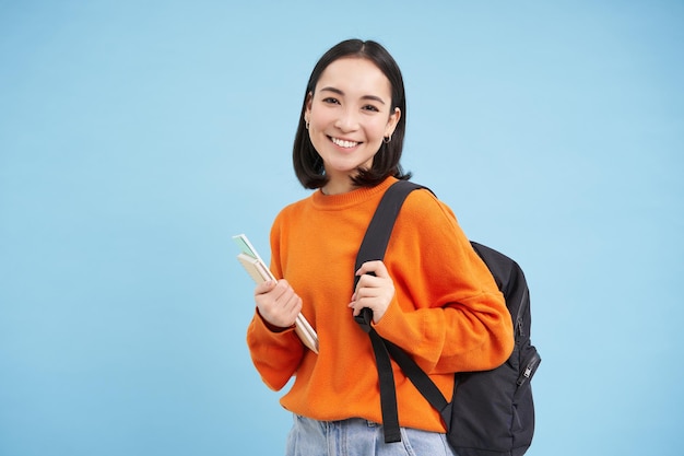 Foto retrato de uma jovem de pé contra um fundo azul