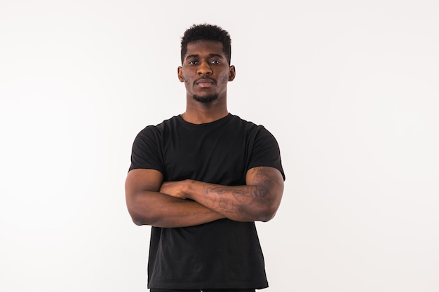 Foto retrato sério de um homem afro-americano em uma camiseta preta olhando de lado no fundo branco do estúdio