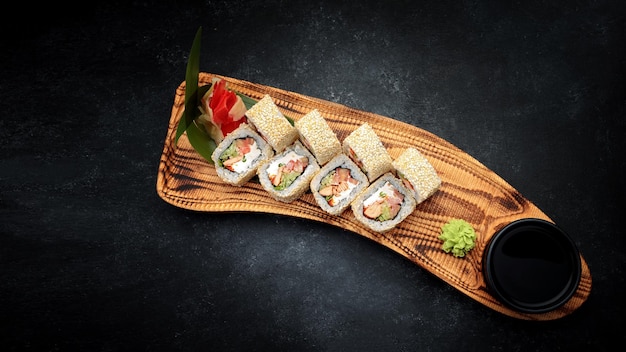 Rolo de sushi com queijo de tomate de salmão frito cebola verde em uma placa de madeira