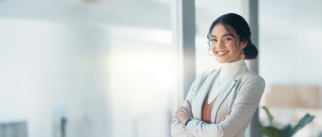 Foto rosto feliz e mulher com os braços cruzados no escritório com orgulho de negócios e trabalho corporativo empresa de sorriso e retrato de uma funcionária com confiança e empoderamento profissional em uma agência