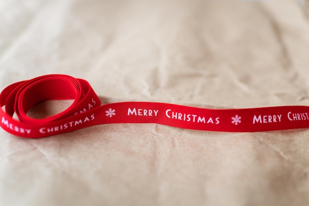 Rotes Band mit der Aufschrift Merry Christmas ausgebreitet auf Bastelpapier Platz für eine Inschrift