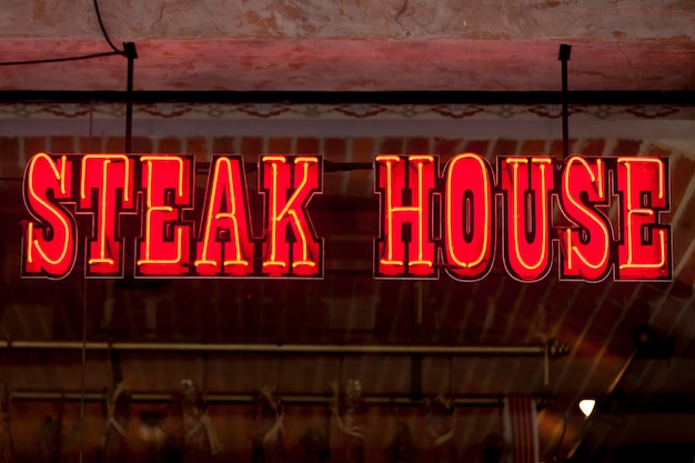 Foto rotes neonlicht formte sich zu den worten steakhouse über dem schaufenster eines restaurants