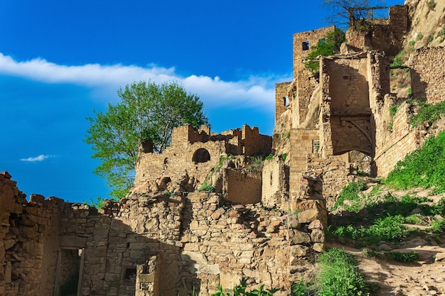 Ruinen von Häuserwänden auf einer Klippe im verlassenen Dorf Gamsutl