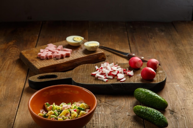 Foto salada em um prato de barro em uma mesa em uma mesa de madeira ao lado de vegetais picados