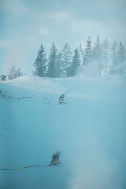 Schneekanone in den Winterbergen. Schneekanone, die künstliche Eiskristalle sprüht. Maschinen, die Schnee machen.