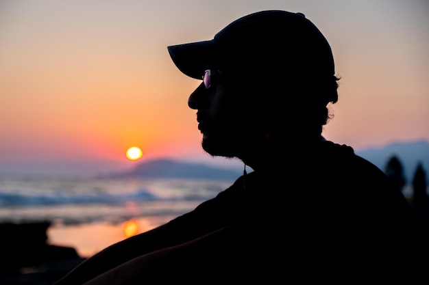 Silhueta adolescente sentado na praia em paz