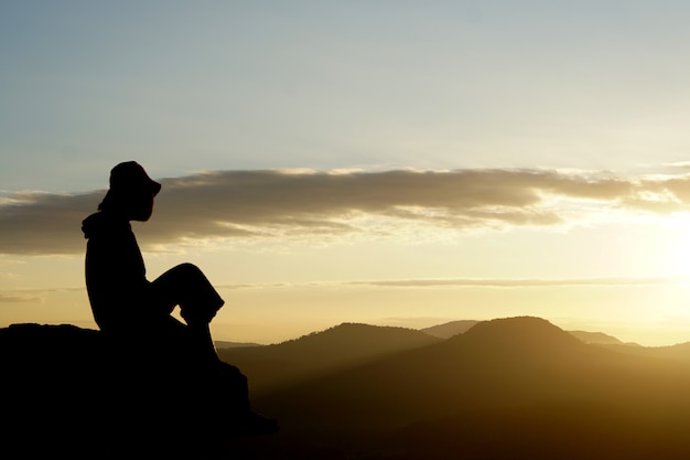 silhueta de mulher asiática levantando a mão para o sol ao anoitecer