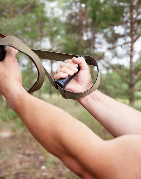 Sportler macht Kraftsportübungen an Gürteln, Outdoor-Fitness