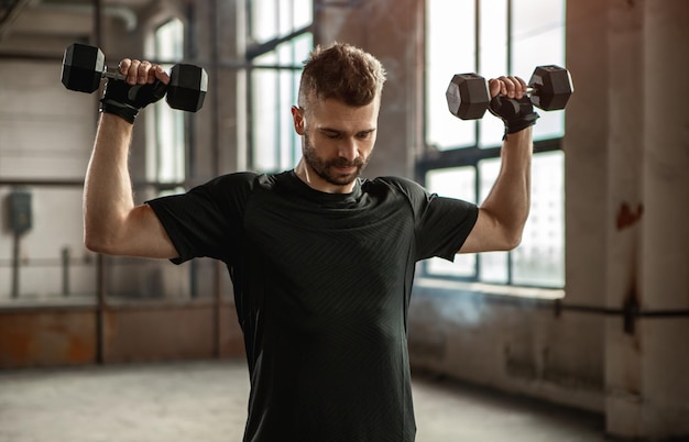 Starker Mann, der mit Hanteln im Fitnessstudio trainiert