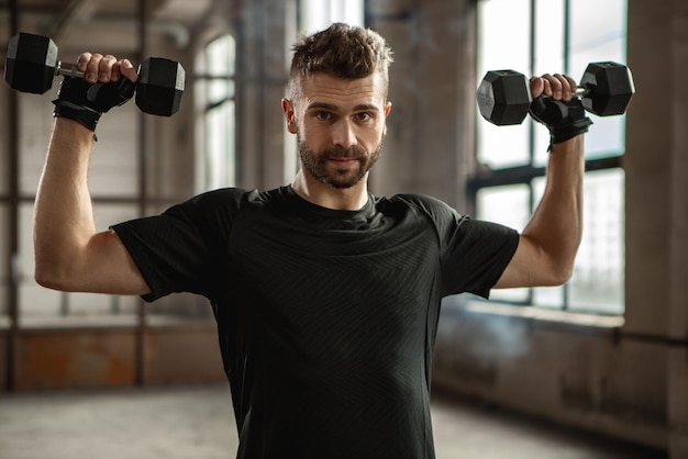 Starker Sportler, der mit Hanteln im Fitnessstudio trainiert