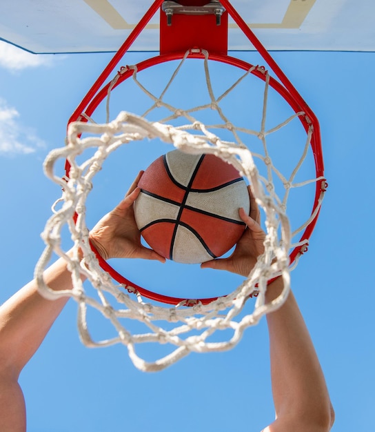 Foto sucesso do esporte. pontuação durante o jogo de basquete. bola passa pela cesta. homem jogando a bola no aro. mãos e basquete. enterrado na cesta. enterrada em movimento. jogador profissional.