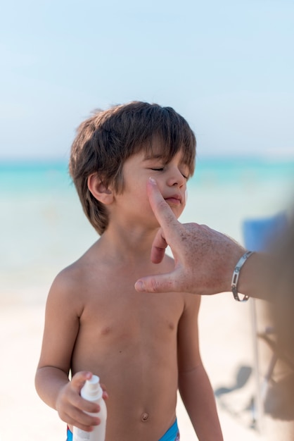 Süsser Boy am Strand mit Sonnencreme