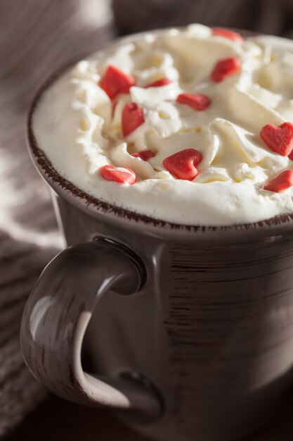 Tasse Kaffee mit Schlagsahne und roten Herzen