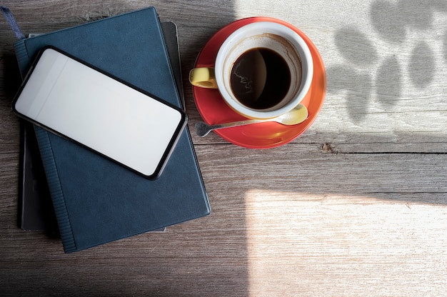 Tela em branco de maquete smartphone branco e café na mesa superior de madeira.