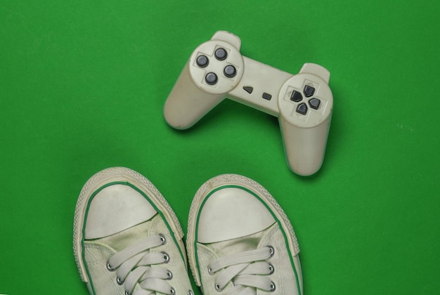 Tênis velhos retrô e gamepad em fundo verde vista superior dos anos 80