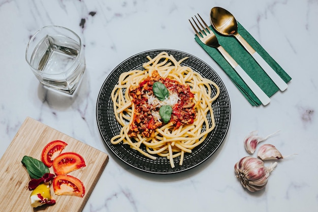 Foto top-ansicht von nudeln mit bolognese-sauce auf einem schwarzen teller mit essgerät