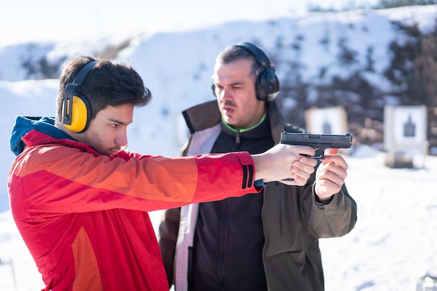 Trainer hilft jungen Menschen beim Kampftraining mit der Pistole zu zielen. Foto in hoher Qualität