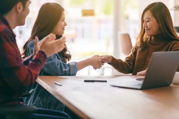 Foto três empresários asiáticos trabalhando e apertando as mãos em uma reunião