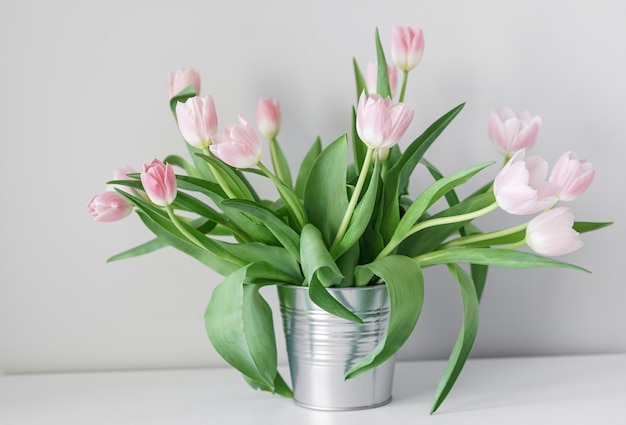 Tulipas brancas da primavera em um vaso abstrato na prateleira, sala interior