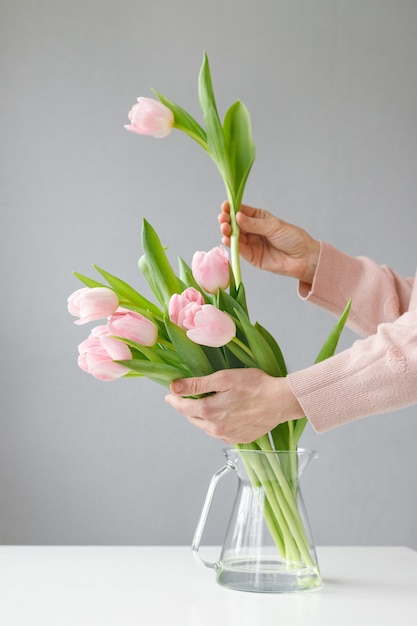 Tulipas rosa com folhas verdes em um vaso de vidro