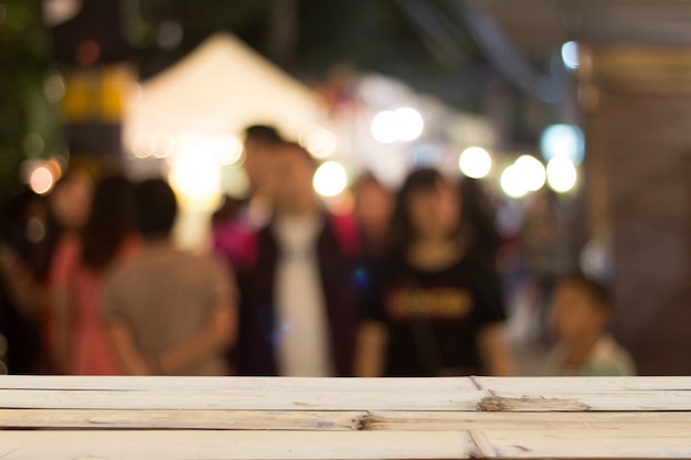 Turva as pessoas na rua de noite e mesa de madeira na fonte